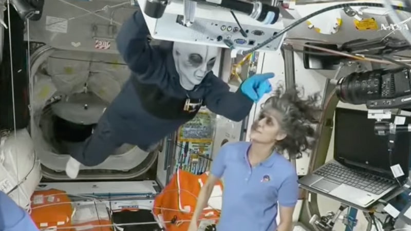 crew inside the ISS, with Nick Hague wearing a Grey alien mask