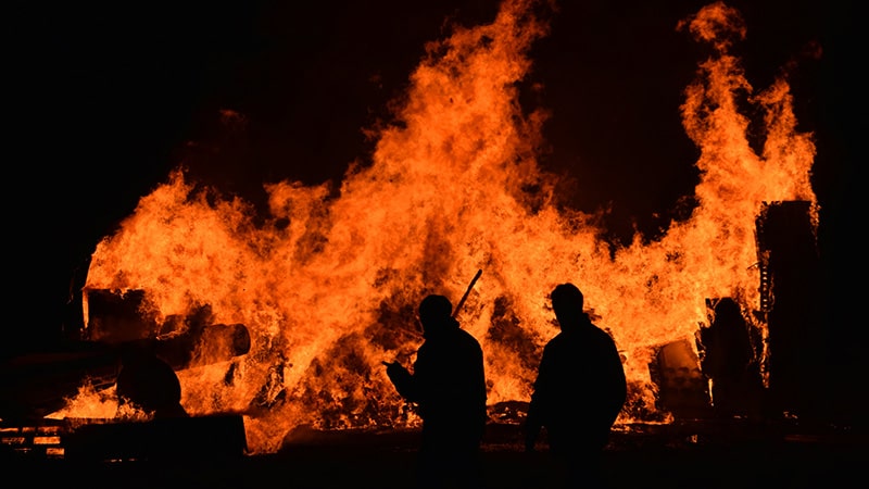 silhouettes standing in front of a raging bonfire