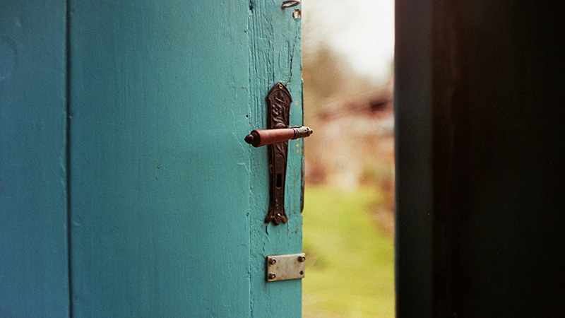 a country door sits ajar, offering a glimpse outside