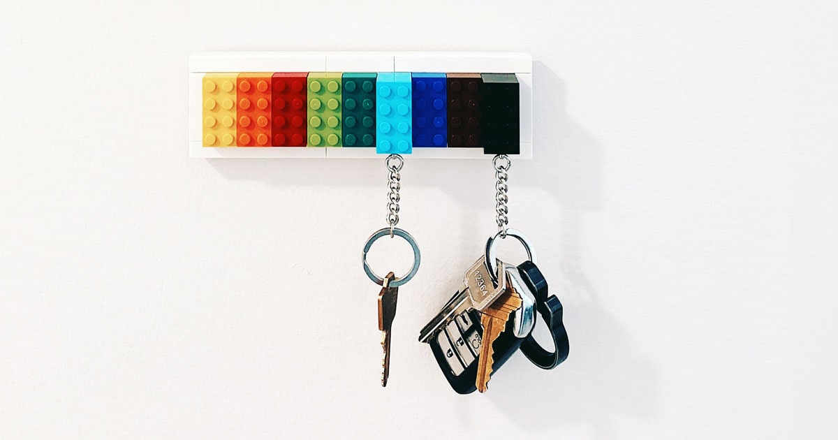 key hanging from a Lego keychain holder mounted on a wall